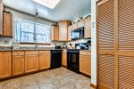 Large U shaped kitchen with double sink, stocked with cookware, flatware, and utensils 
